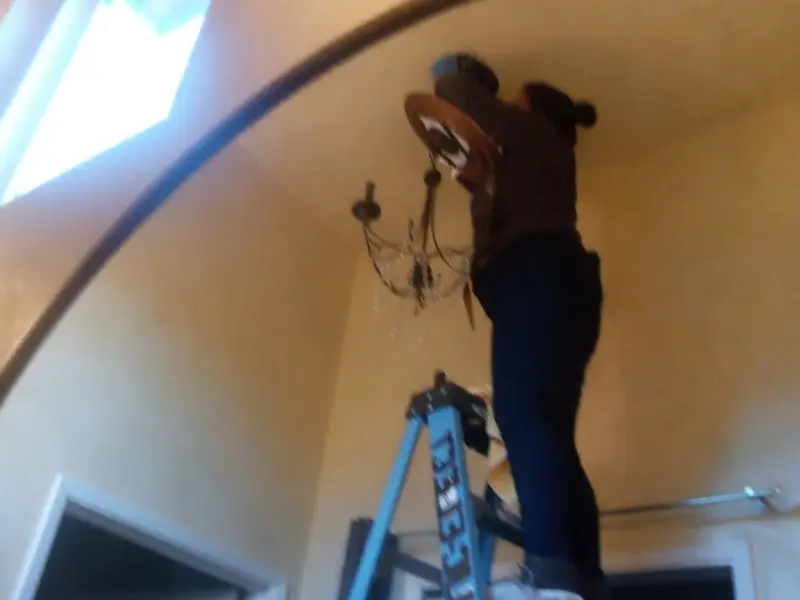 Electrician installing a chandelier in a Heber residence